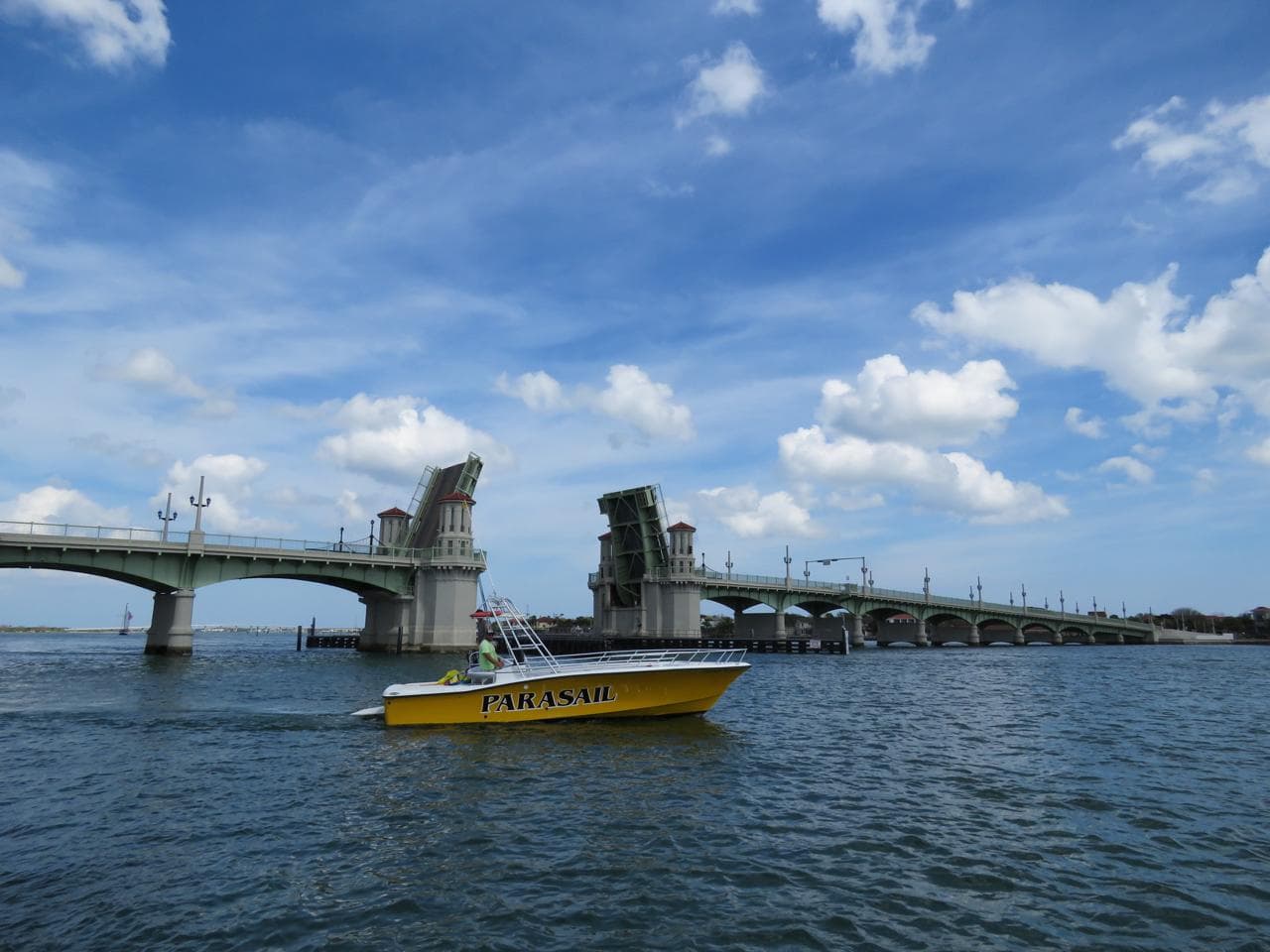 The yellow St. Augustine Parasail boat idling on Matanzas Bay with the Bridge of Lions raised behind it.